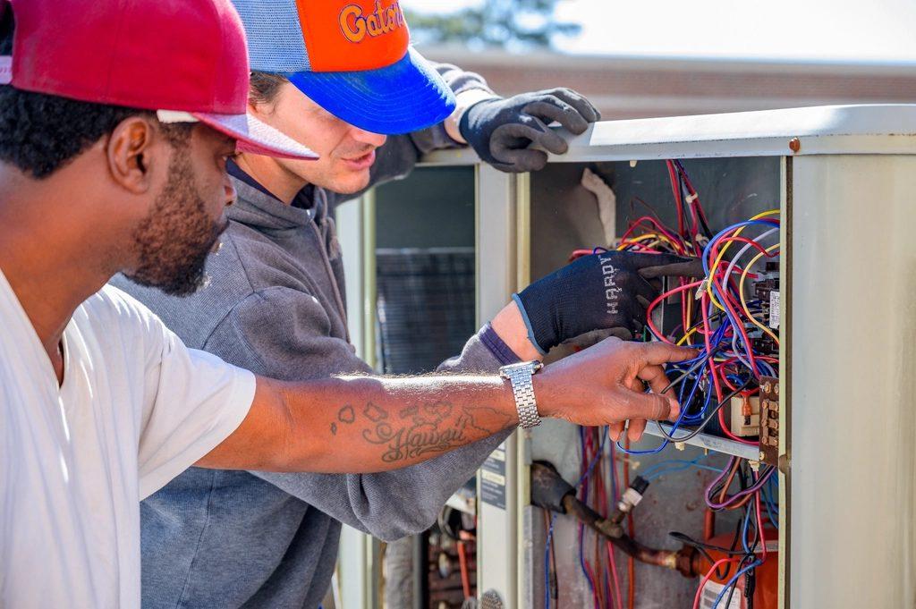 Dois técnicos revisando painel elétrico aberto